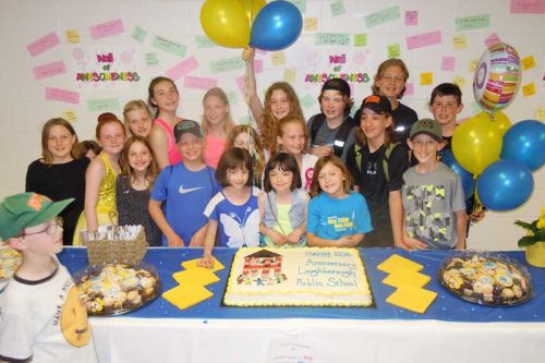 LPS students pose in front of the celebratory cake, which was later cut by John and Ginny Trousdale 